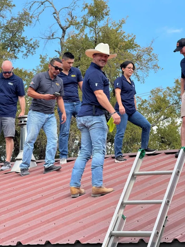Ark Roofer founder Luke Secora with his team on a metal roof in Central Texas