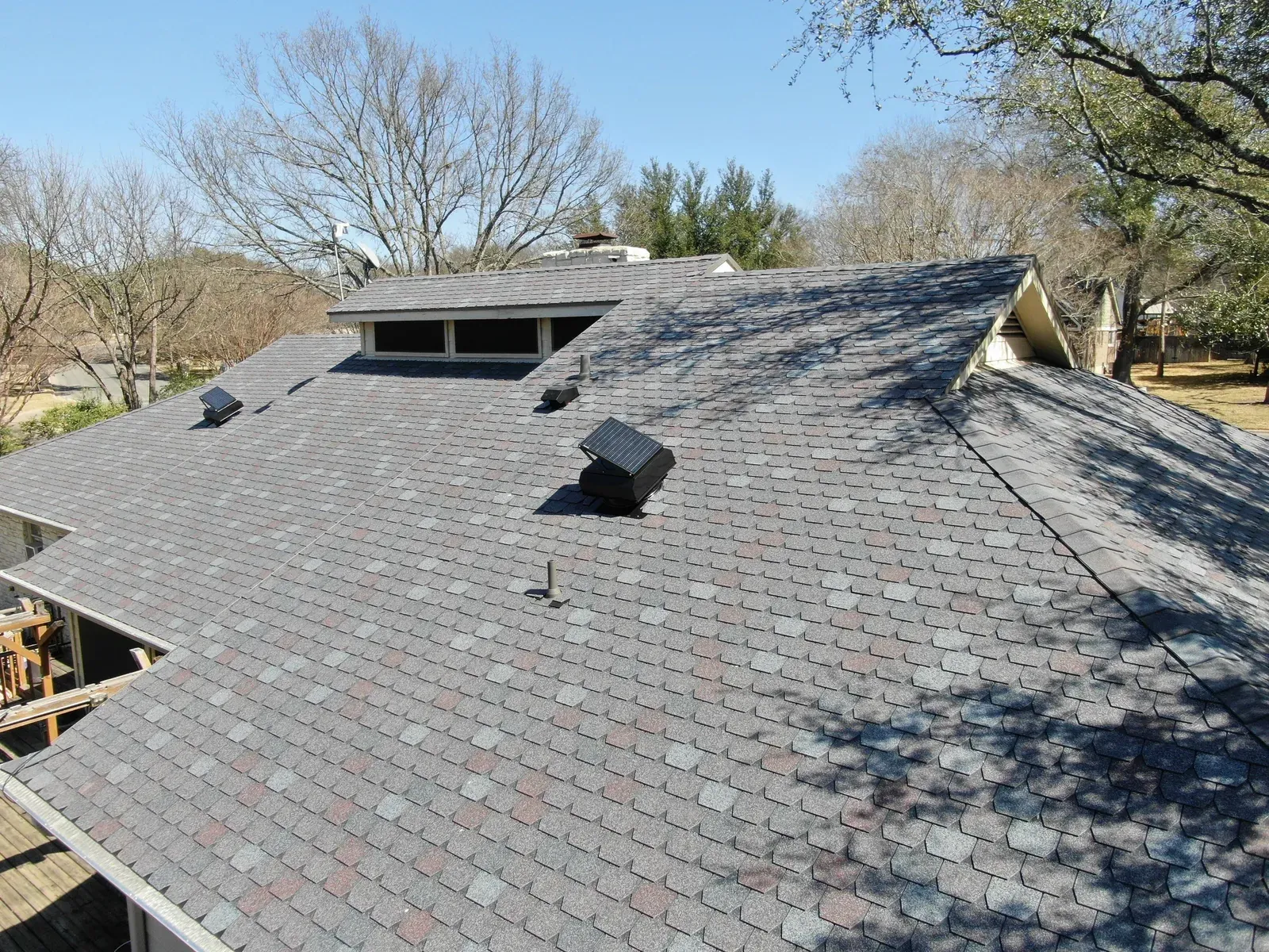 Gray shingle roof with solar attic fans