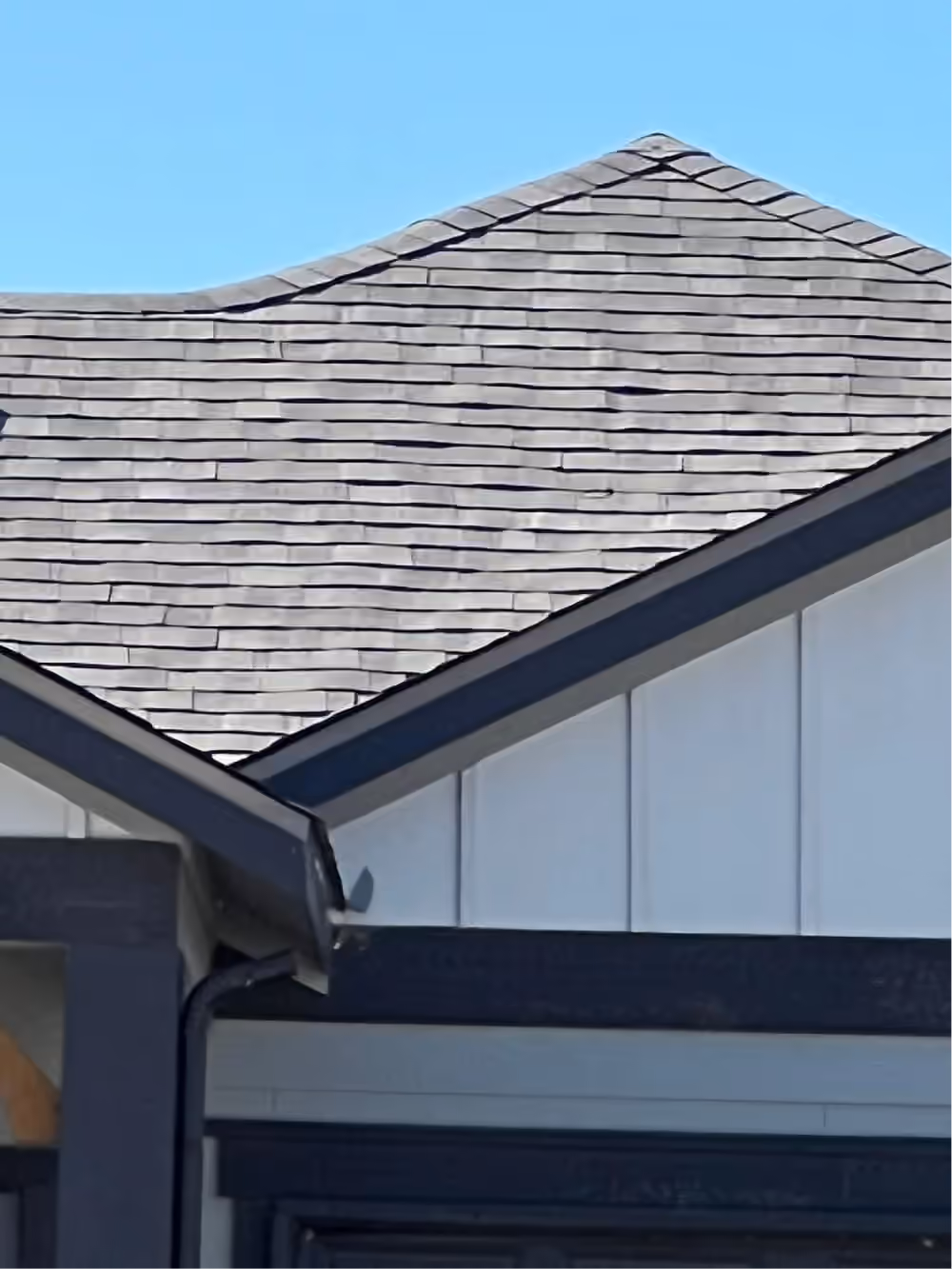 Gray shingles along the roof edge above a gutter