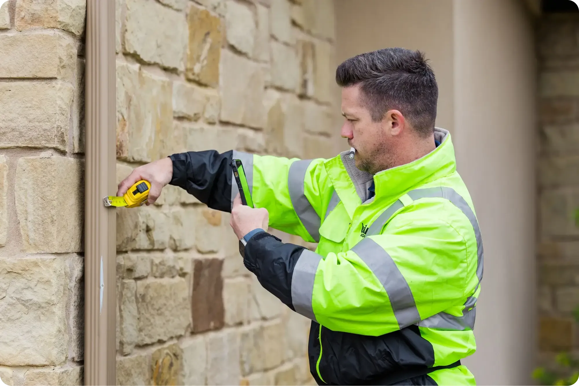 Ark inspector measuring a downspout with a tape measure for an estimate